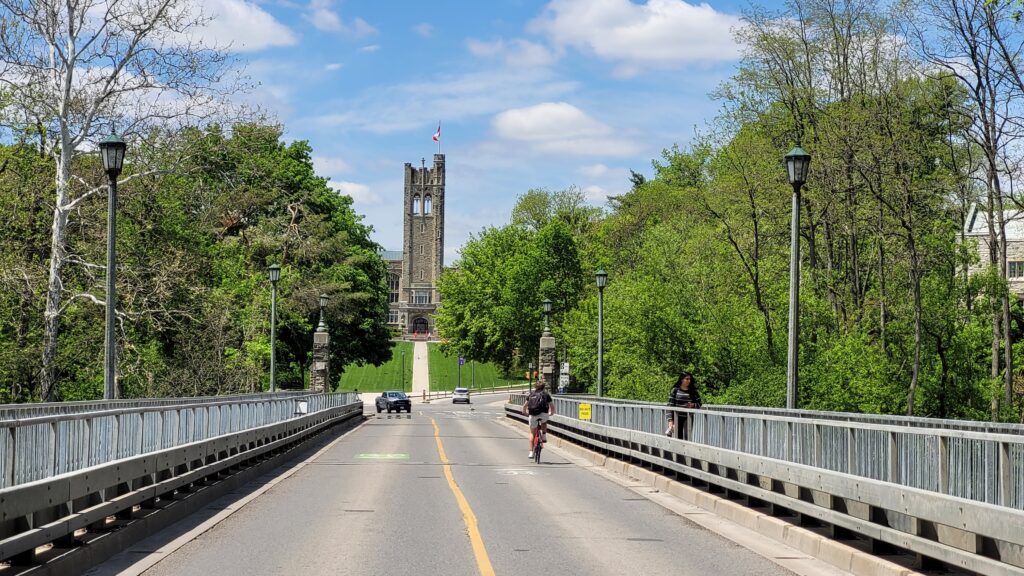 Middlesex County Memorial Tower is in the distance. University Drive with pedestrians, bicycles, and cars in the foreground.