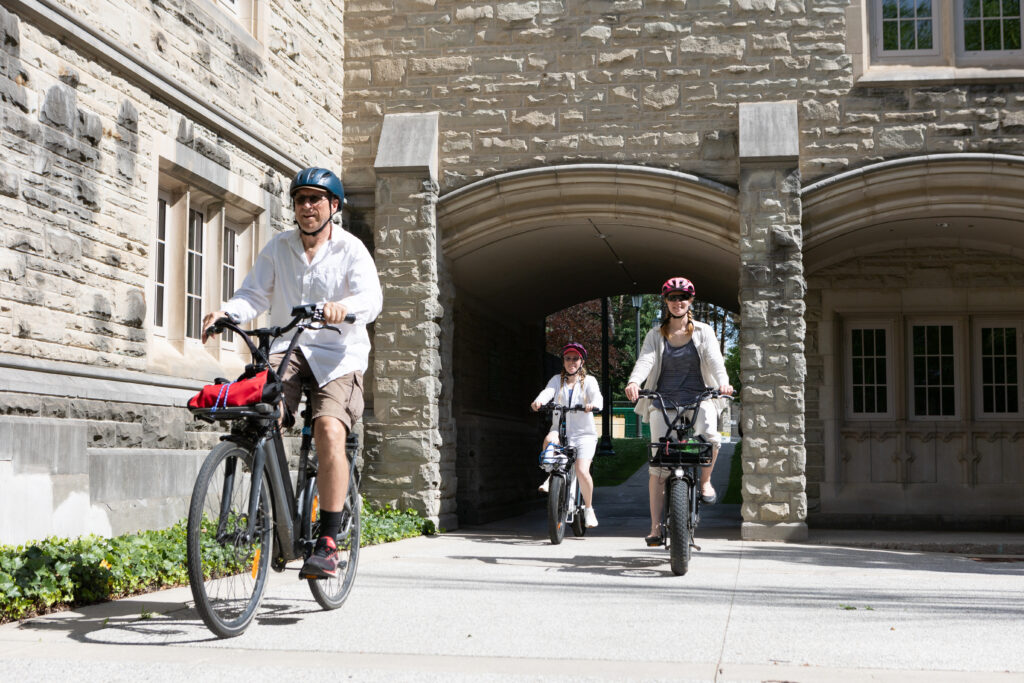 Three cyclists ride under a Gothic Arch.