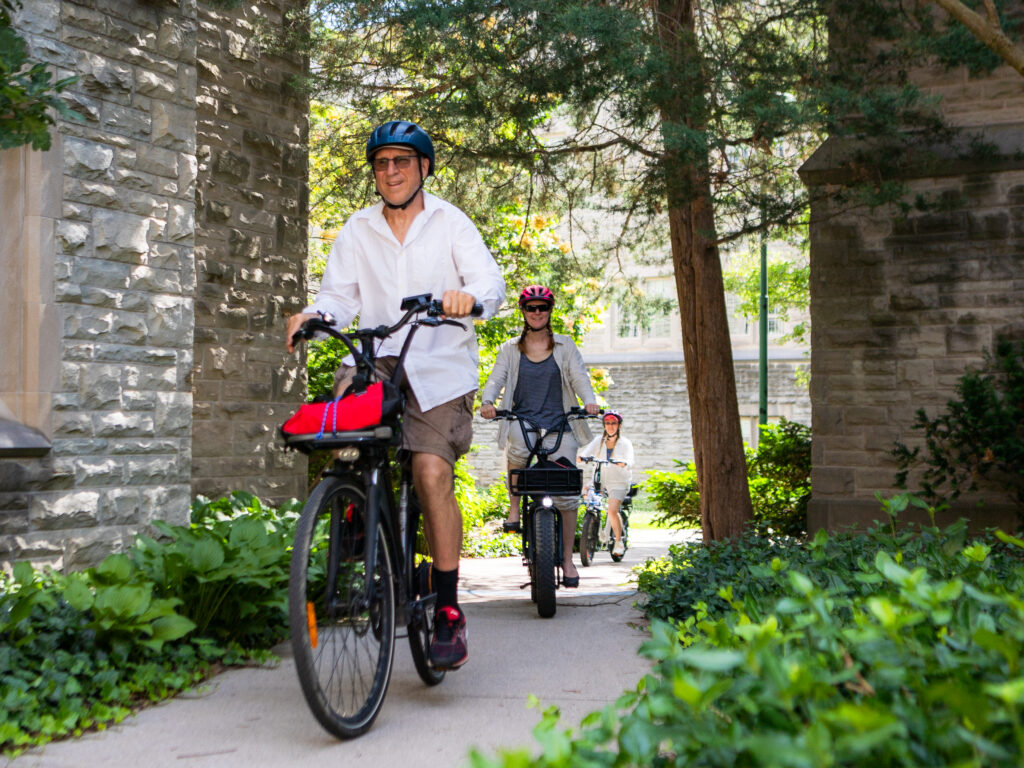 View of three cyclists passing between two massive stone buildings.