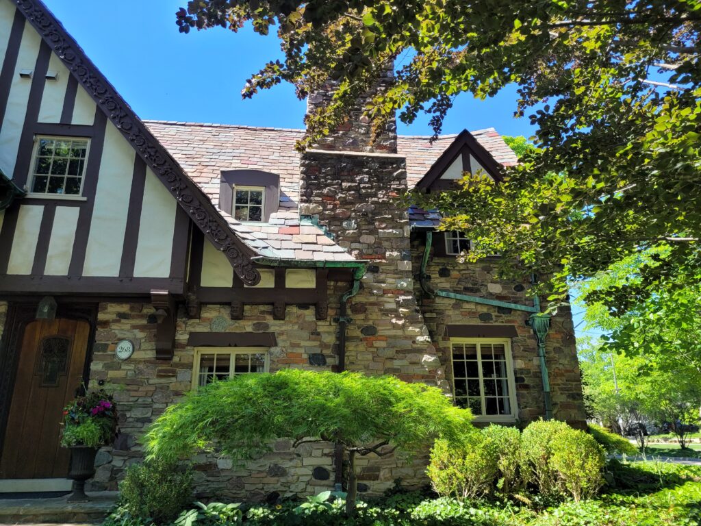 Half-timbers with whitewashed walls in between, steeply pitched roofs, and elaborate chimneys are all defining characteristics of Tudor Revival homes.
