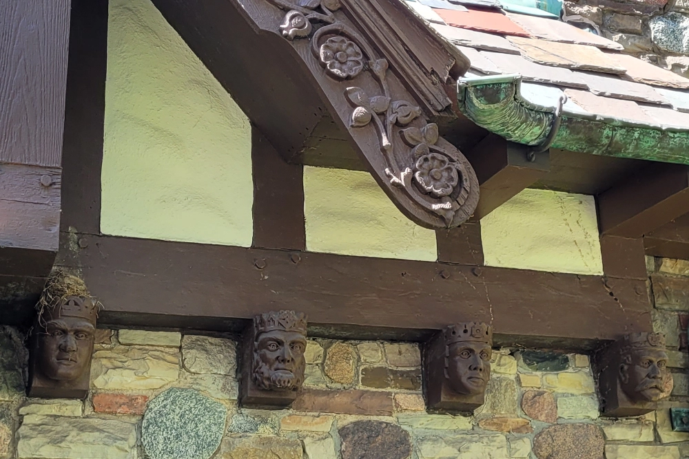 This close-up photo shows the four distinct Tudor Heads (below) and the decorative bargeboards with carved roses (above).