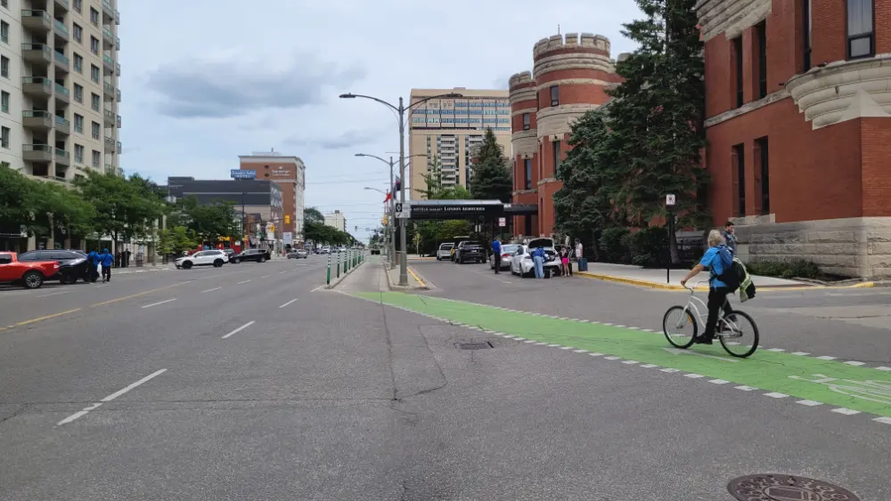 Dedicated bicycle lane in front of the hotel, with a man on a bicycle riding by.
