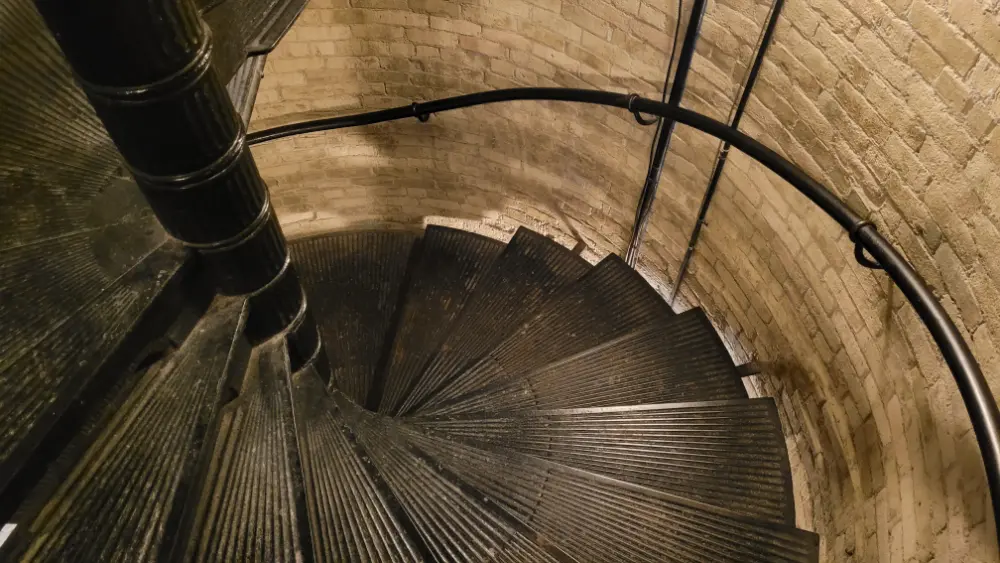 From the second floor, a circular wrought iron staircase winds its way downward.