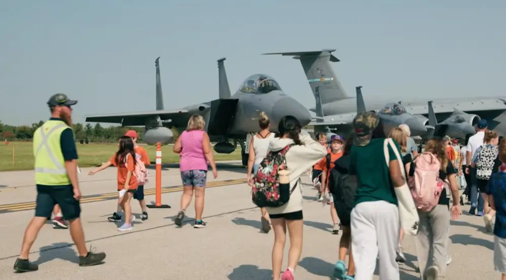 Crowds on the tarmac walking towards static airplane displays.