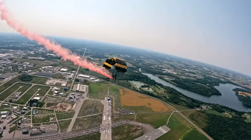 View over the London airfield. Fanshawe Lake is visible in the distance and parachutist trailing orange smoke in foreground.