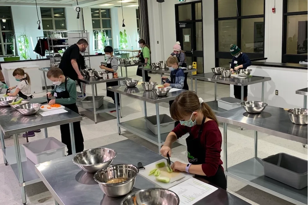 Children about 10 years old learning to cook in a commercial style kitchen.