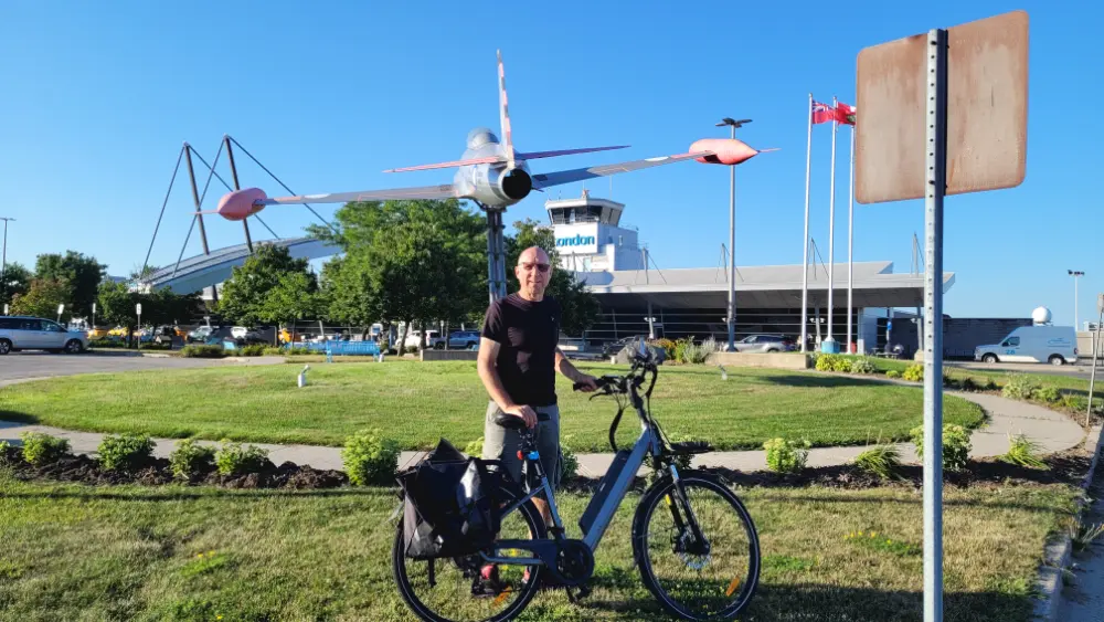 The author, Lawrence Durham, standing in front of the main terminal building at London International Airport with his bicycle.