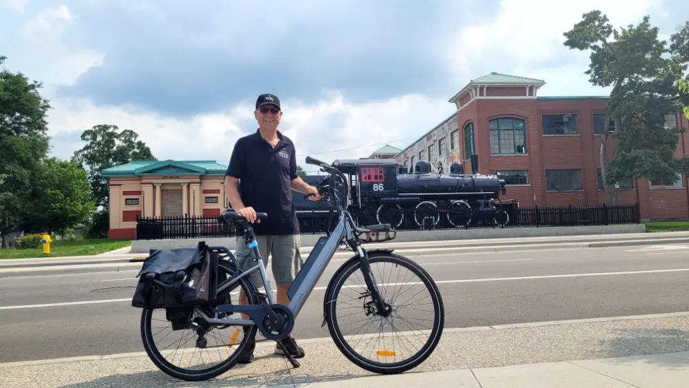Author, Lawrence Durham, with his bicycle, standing in front of an old steam engine on display on Dundas Street.