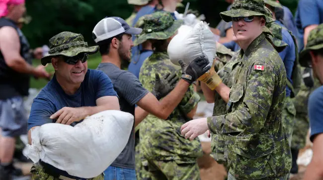 Canadian military reservists help flood victims with moving sandbags.
