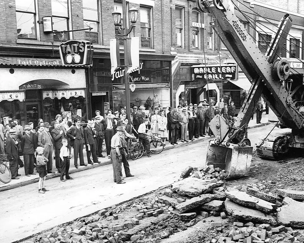 Excavator ripping up streetcar tracks on Dundas St, 1941 in front of crowds of curious onlookers.