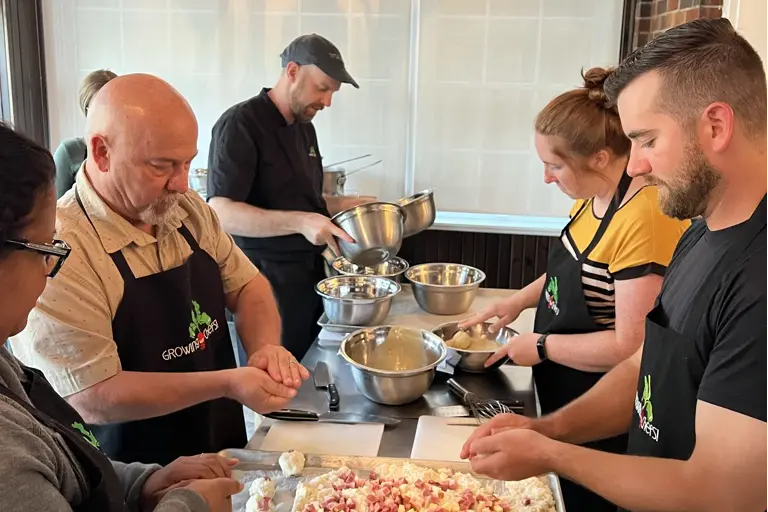 A group of adults preparing a meal in the Growing Chefs kitchen.