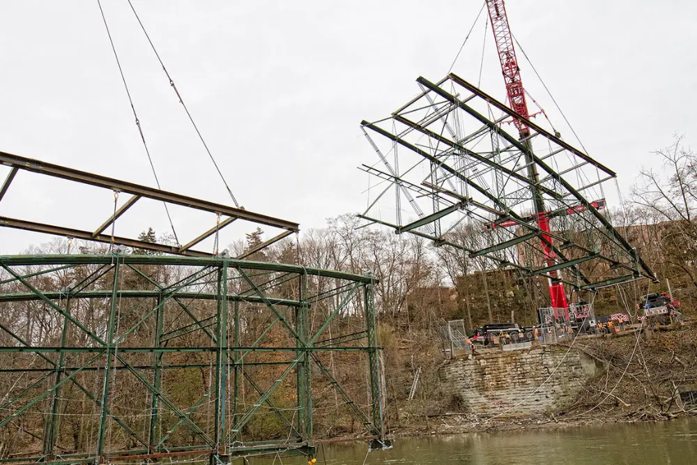Half of the Blackfriars Bridge sails above the urban canopy while suspended by chains.