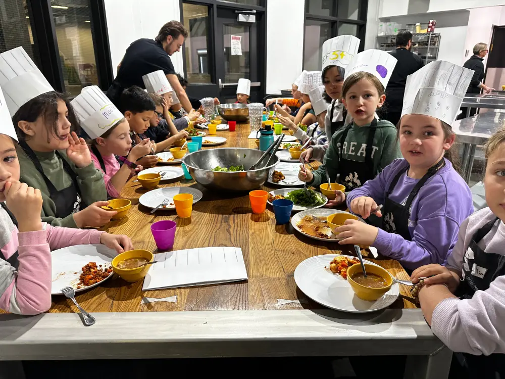 A group of 10 year old aspiring chefs sitting down to enjoy the meals they prepared.