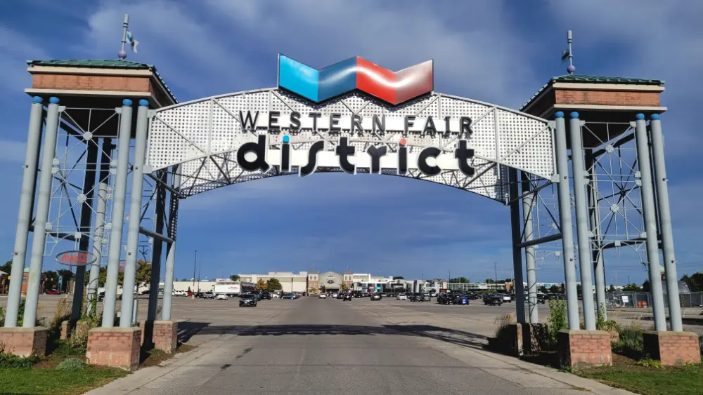 Gateway entrance to the Western Fair District, with the large parking lot and buildings in the background.