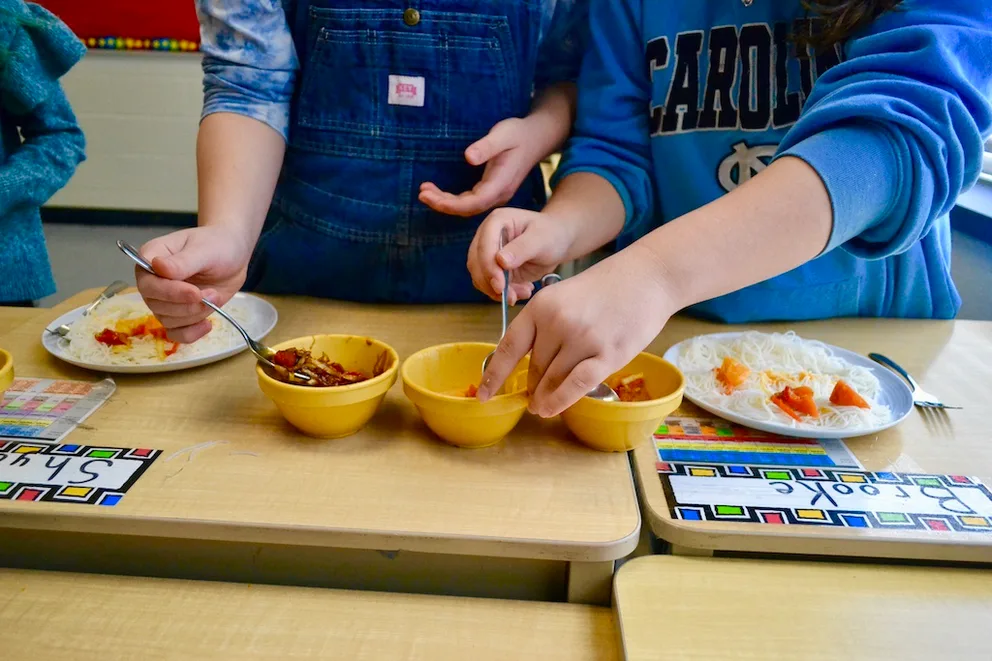 Children putting food into a variety of bowls.